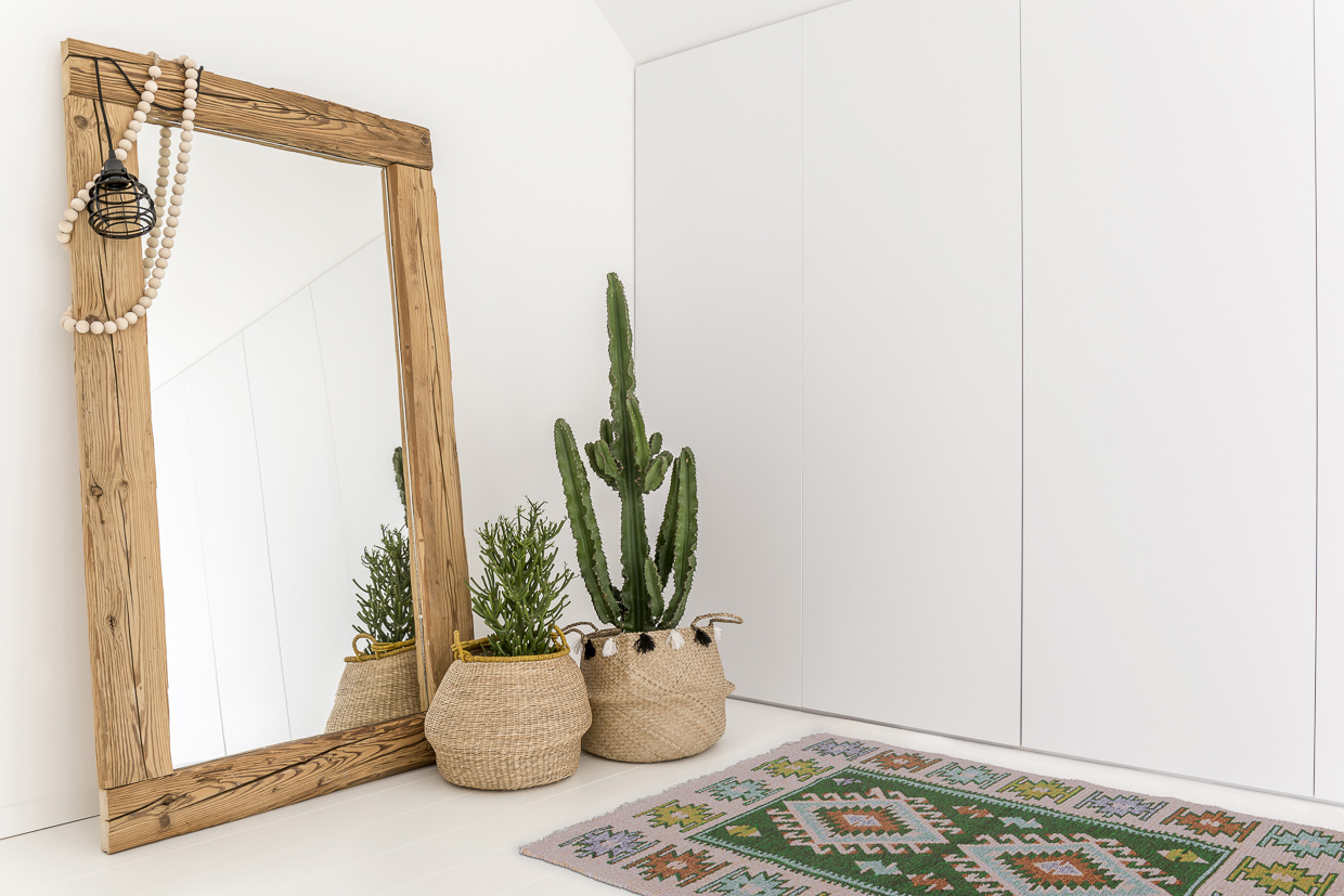 White room with mirror with wooden frame and decorative cactus and our vintage kilim rug